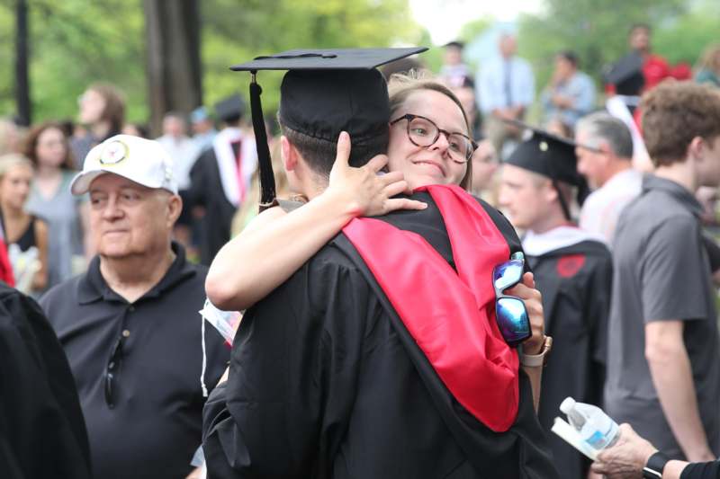 a woman hugging a man in graduation gown