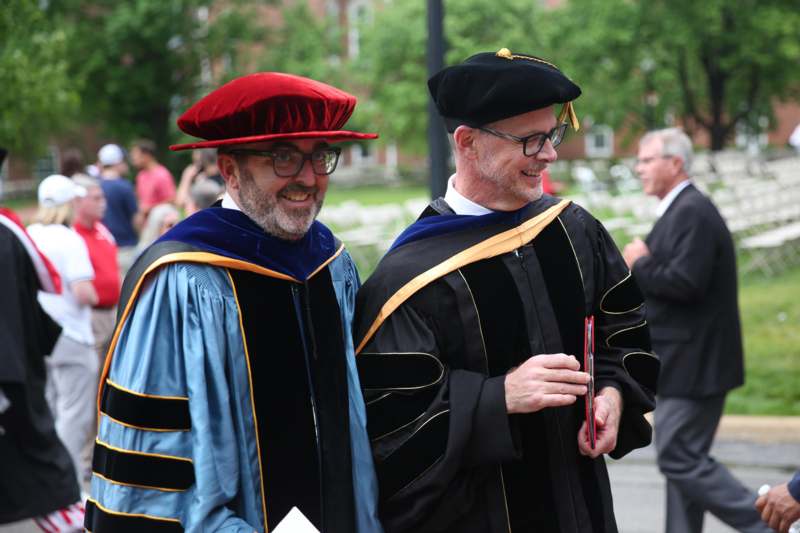 two men wearing graduation gowns and hats