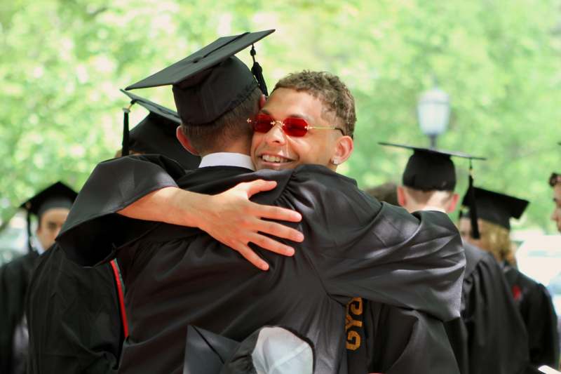 a man in a cap and gown hugging another man