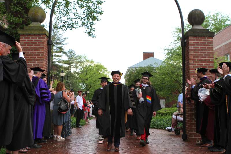 a group of people in graduation gowns and caps walking down a brick path