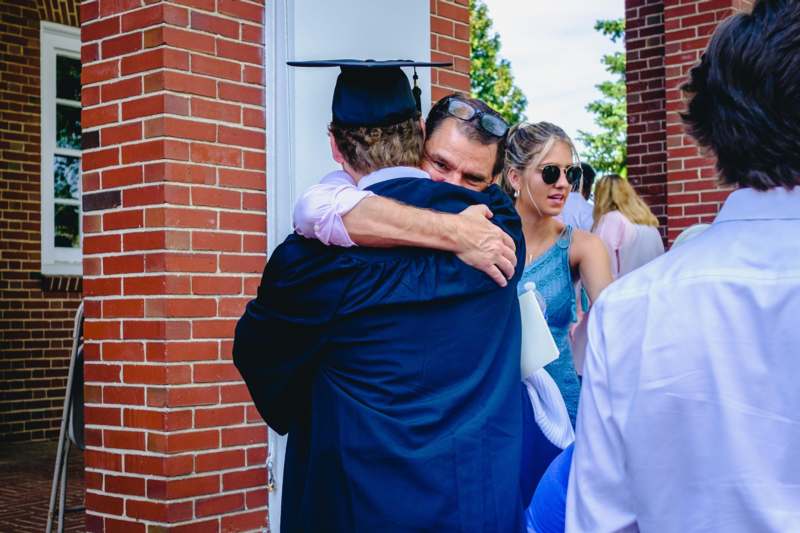 a man in a graduation cap hugging a man in a cap