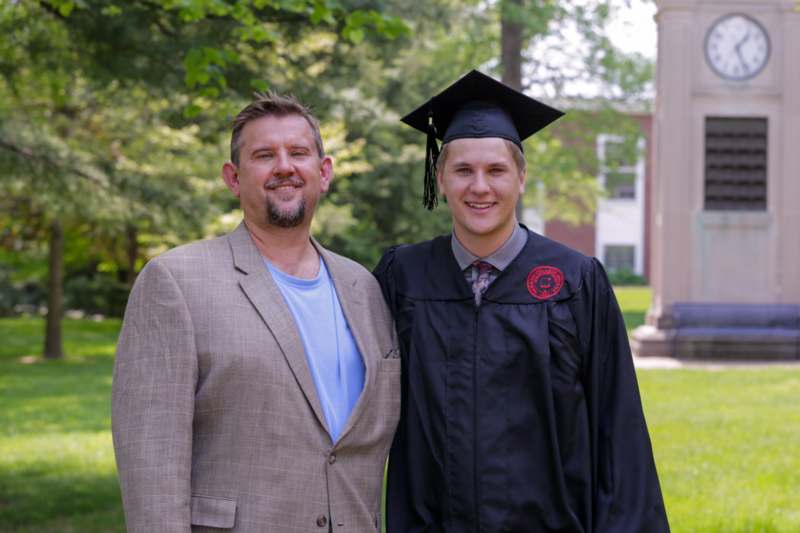a man standing next to a man in a graduation cap