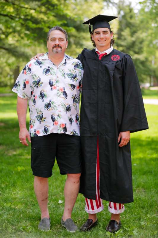 a man standing next to a man in a graduation gown