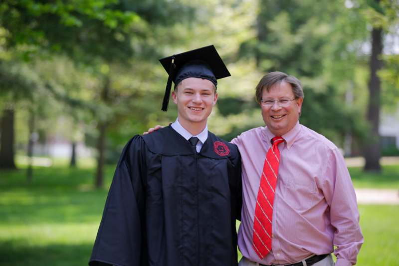 a man in a cap and gown standing next to a man in a cap and gown