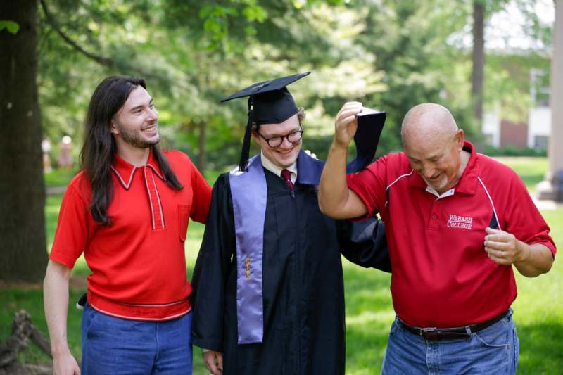 a man in a cap and gown smiling with a man in a red shirt