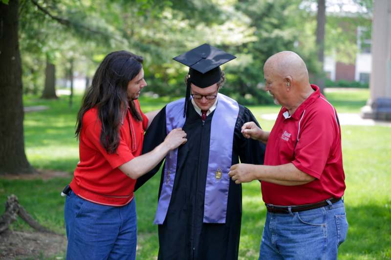 a group of people standing around a graduation gown