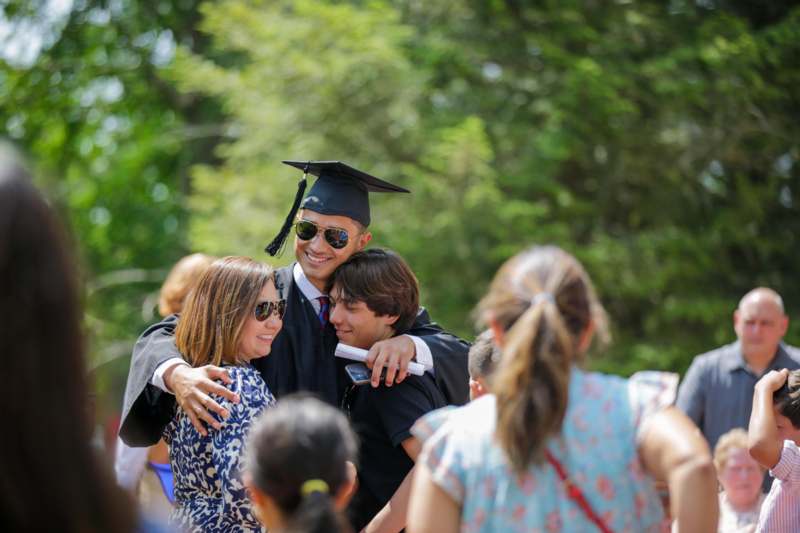 a man in a cap and gown hugging a woman in a crowd