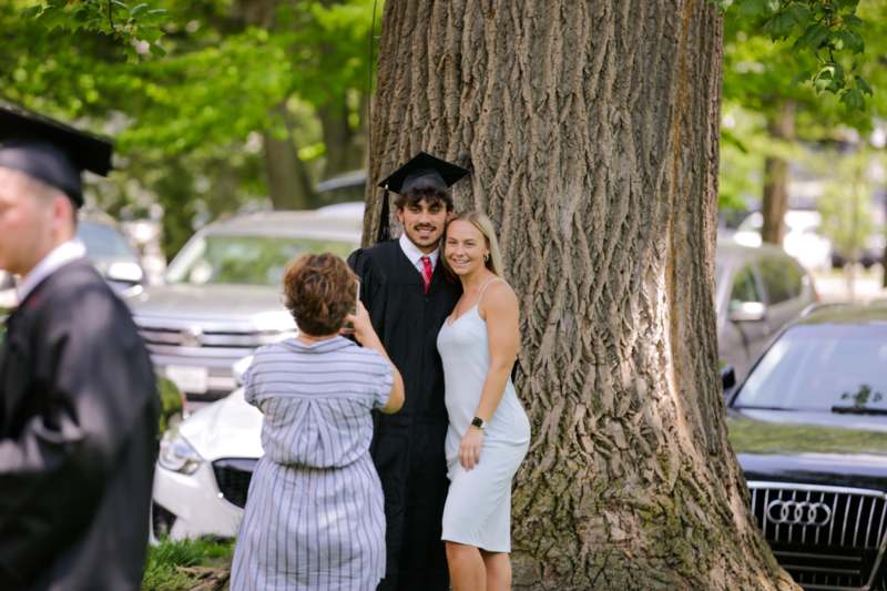 a man in a graduation cap and gown standing next to a woman
