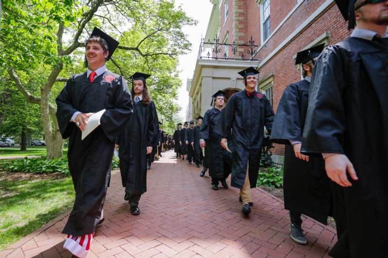 a group of people in graduation gowns and caps walking down a sidewalk