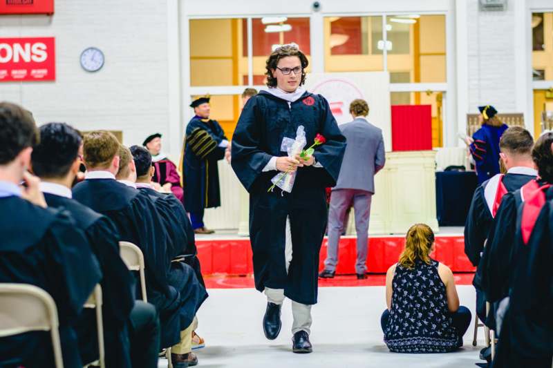 a man in a graduation gown walking towards a group of people