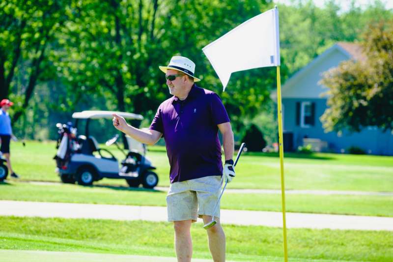 a man in a hat and sunglasses holding a golf club
