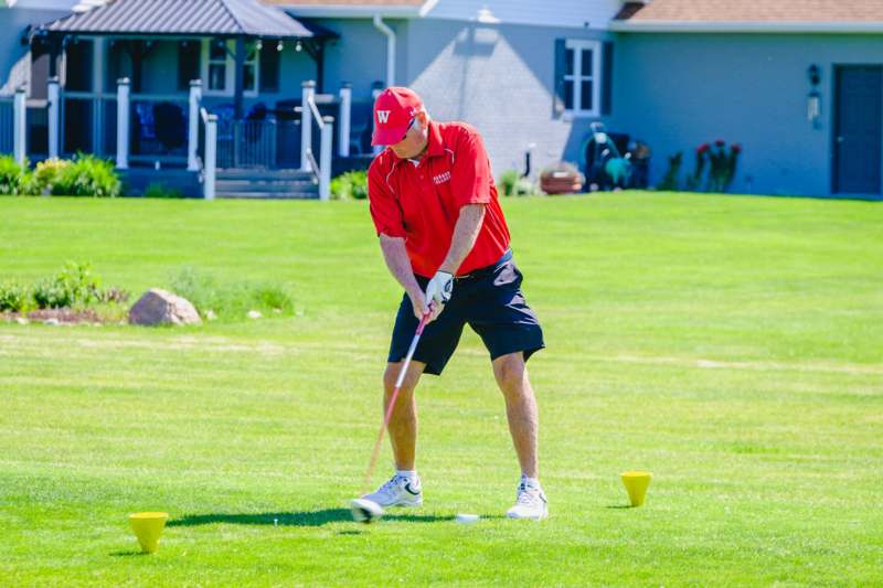 a man in a red shirt and black shorts playing golf