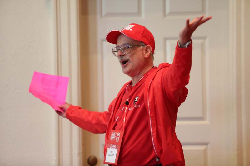 a man in red jacket holding a pink piece of paper