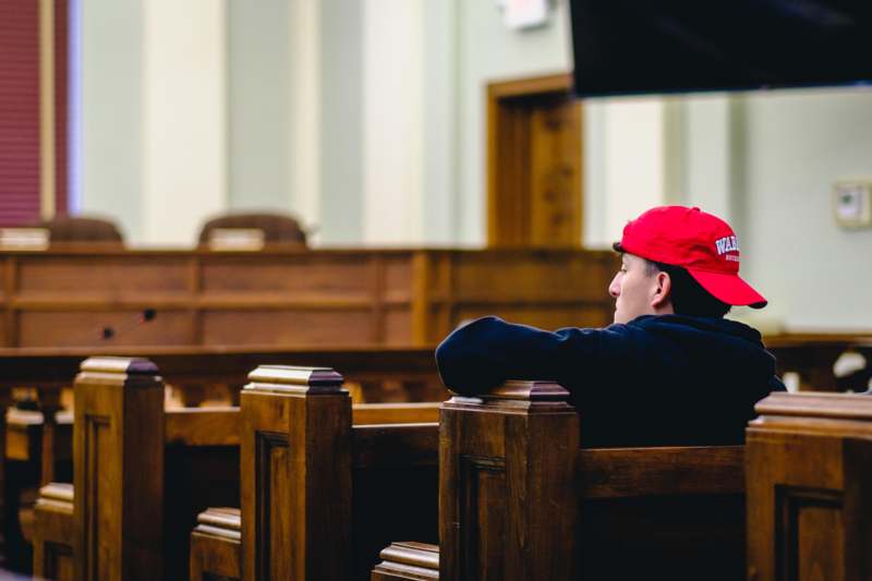 a man in a red hat sitting in a pew