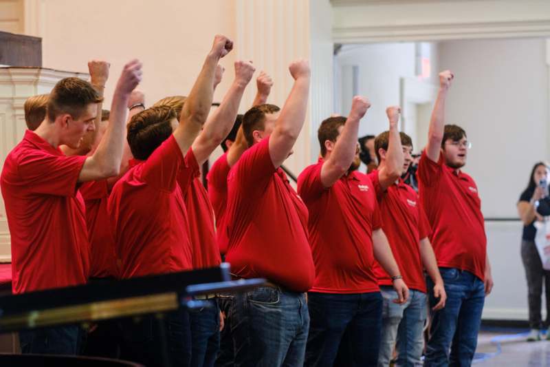 a group of men in red shirts raising their fists