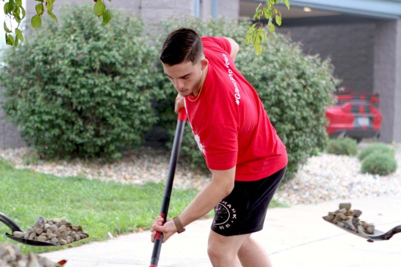 a man in a red shirt holding a shovel