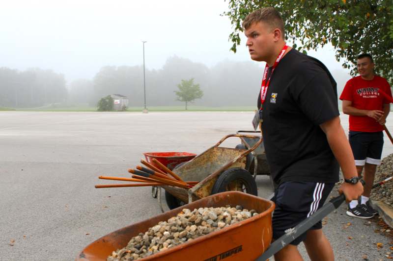 a man pushing a wheelbarrow full of rocks