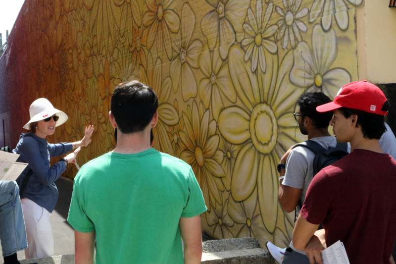 a group of people standing in front of a wall with a flower pattern