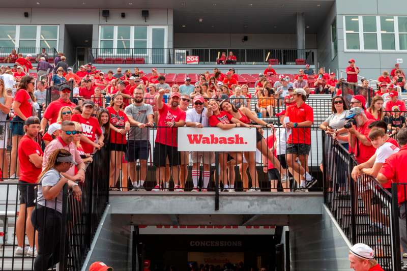 a group of people in red shirts standing on a railing in a stadium