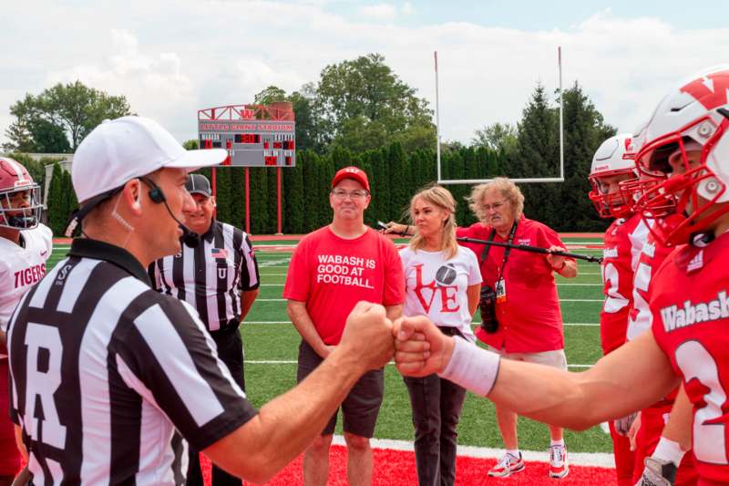 a football coach shaking hands with a group of people on a football field