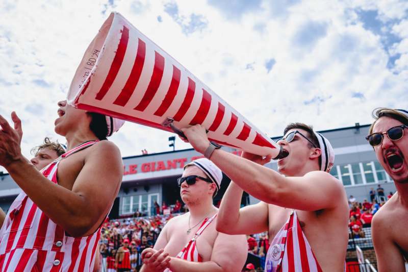 a group of men wearing red and white striped shirts and holding megaphone