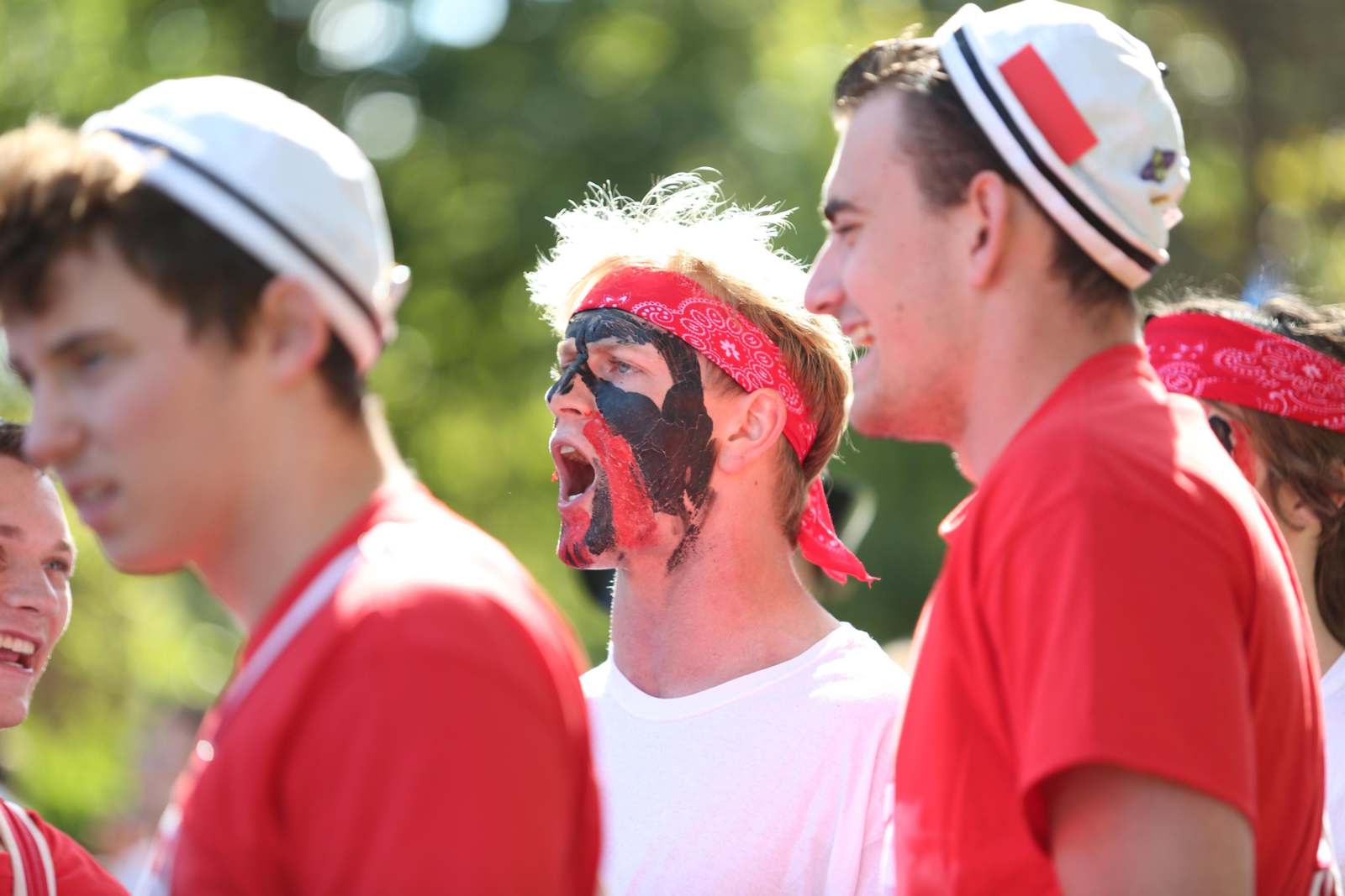 a group of men wearing red shirts and black face paint