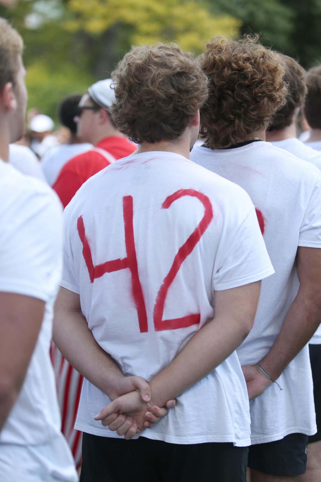 a group of people wearing white t-shirts with red writing on their back