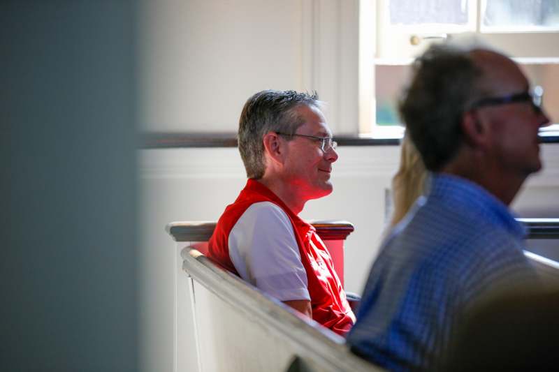 a man in a red vest sitting in a church pew