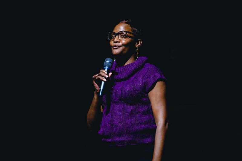 a woman in a purple shirt holding a microphone