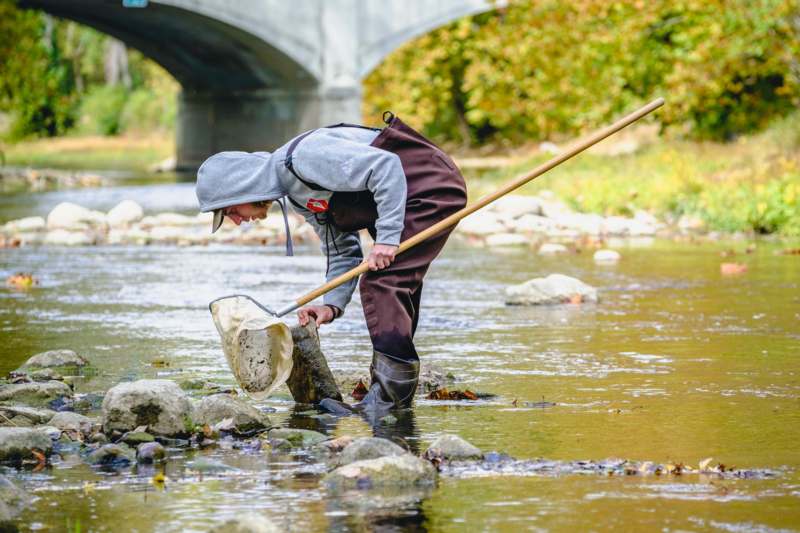 a man in a hoodie holding a net in a river