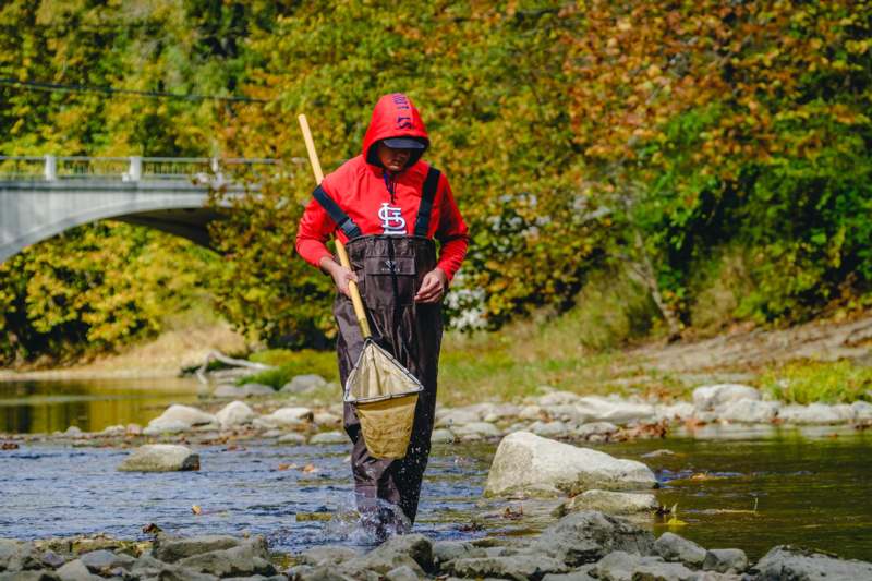 a man in a red hoodie holding a net in a river