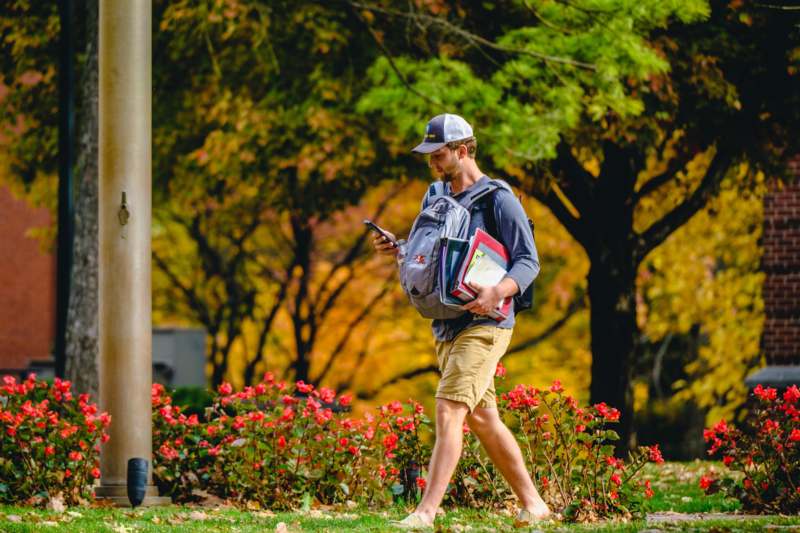 a man walking with a backpack and books