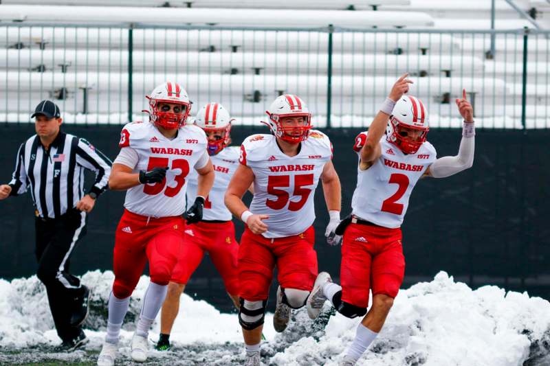 a group of football players running in snow