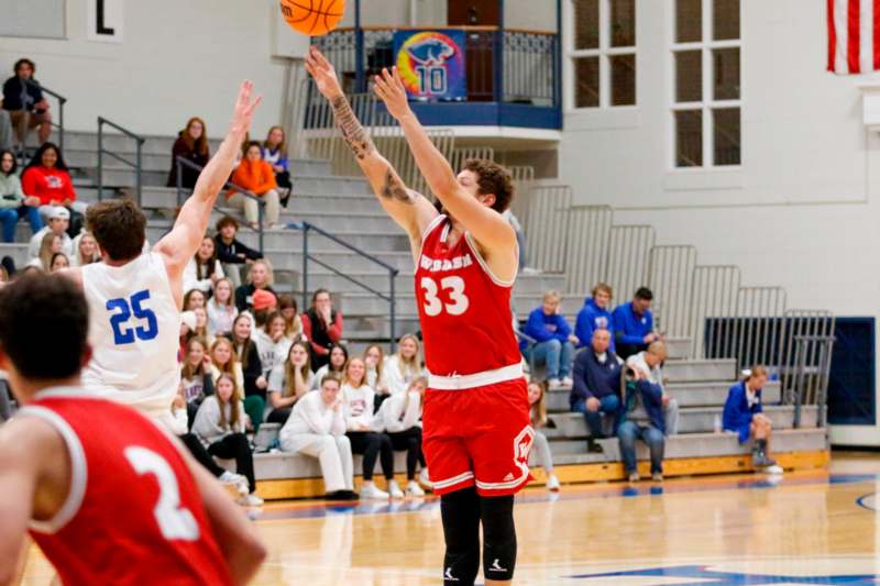 a basketball player in red uniform and a white jersey with a red ball in the air