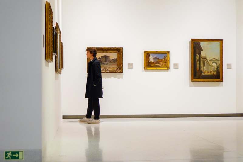 a man looking at a painting on a wall
