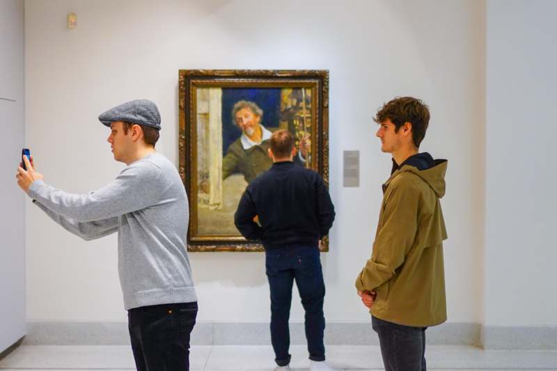 a group of men looking at a painting