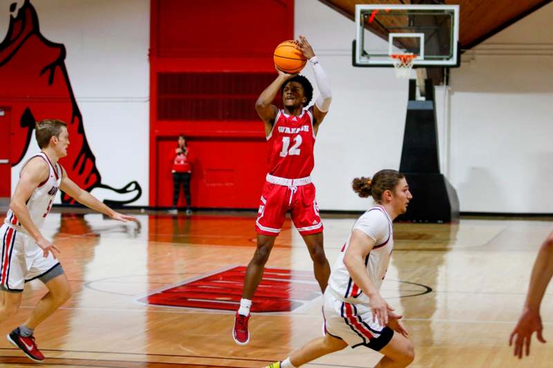 a basketball player in red uniform jumping to shoot a basketball