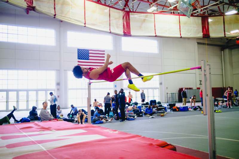 a man jumping over a pole in a gym