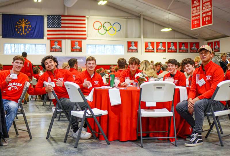 a group of people sitting at tables in a room with red shirts