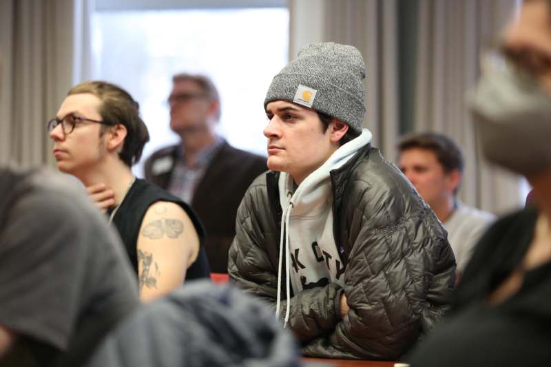 a man in a beanie and jacket sitting at a table