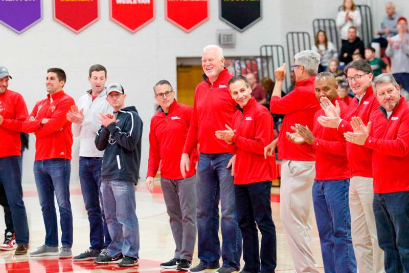 a group of men in red shirts standing on a basketball court