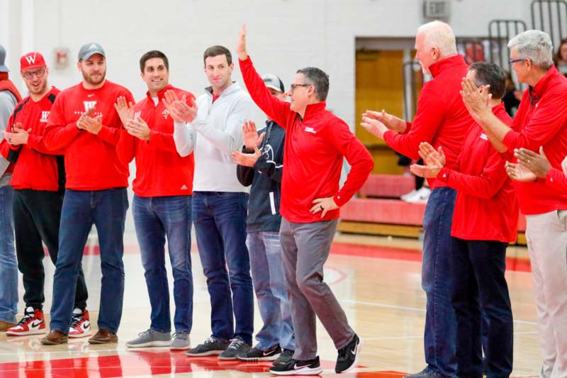 a group of men in red shirts standing on a court with their hands up