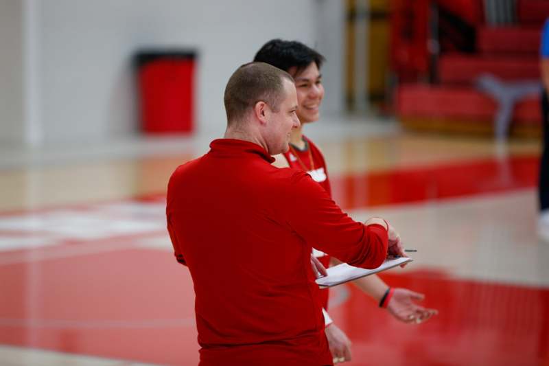 a man in red shirt talking to another man in a gym