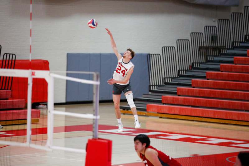 a man in a uniform jumping to hit a volleyball