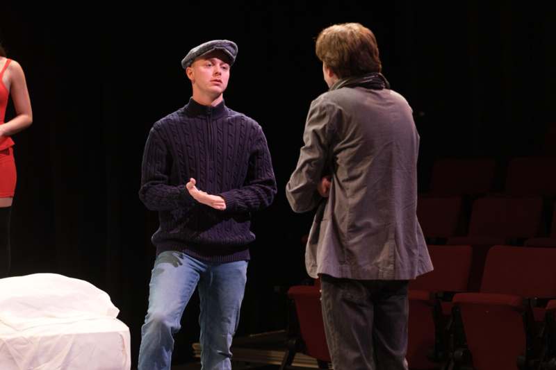 a man standing on a stage with another man in the back