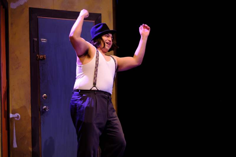a man wearing suspenders and a hat dancing on stage