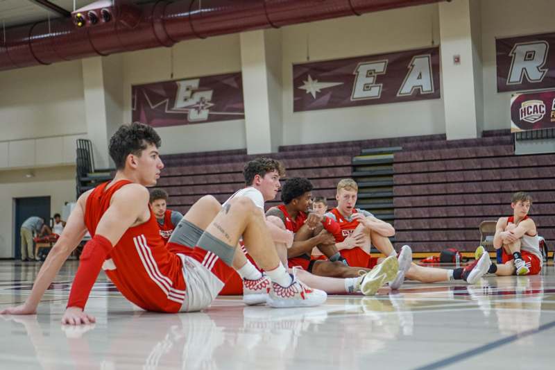 a group of men sitting on the floor in a gym