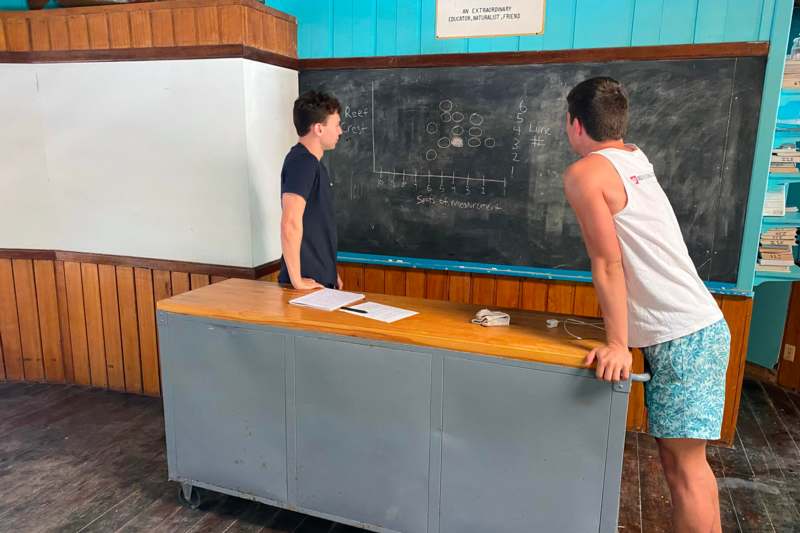 two men standing in front of a chalkboard