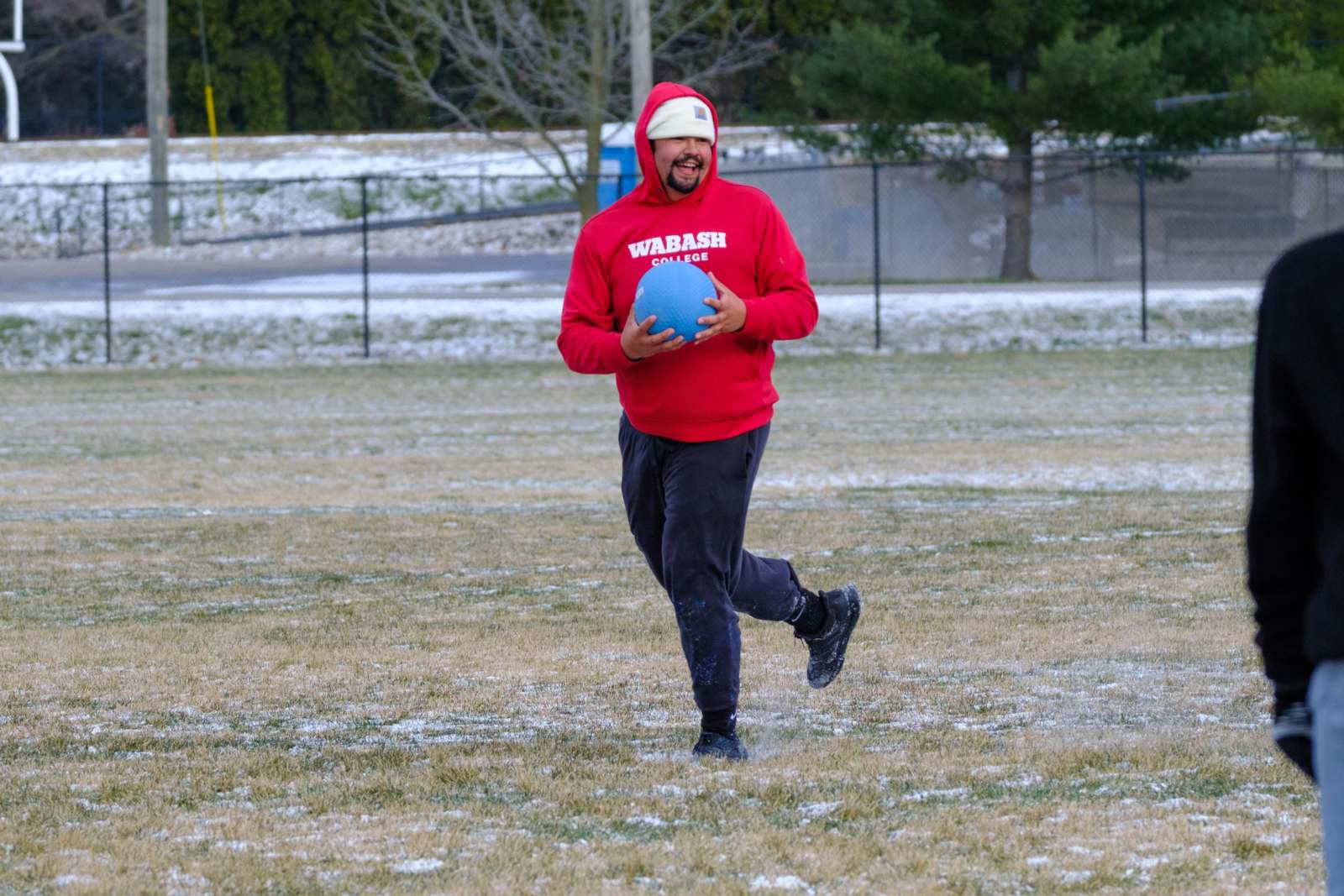 a man in a red hoodie holding a blue ball in a field