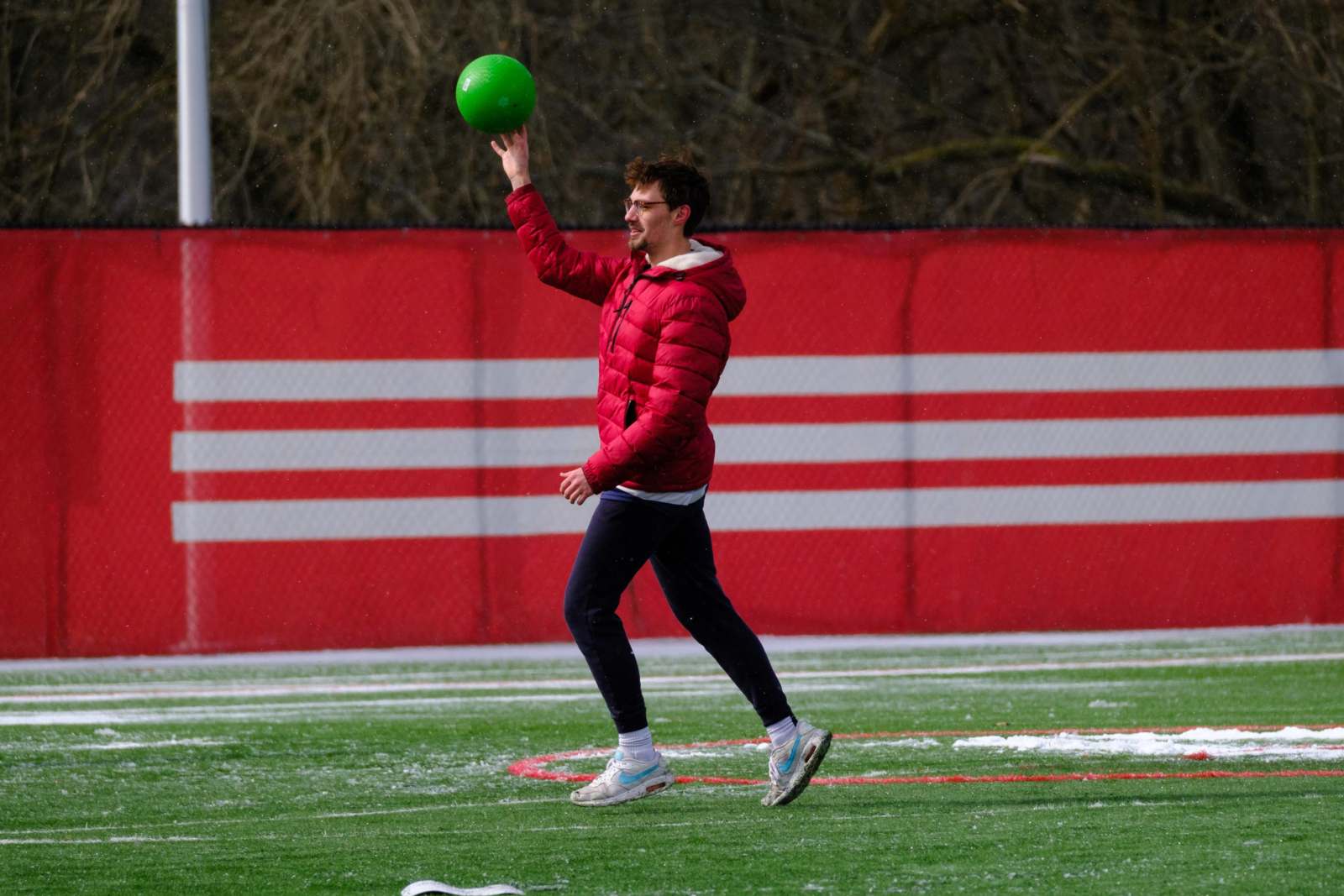 a man in a red jacket holding a green ball
